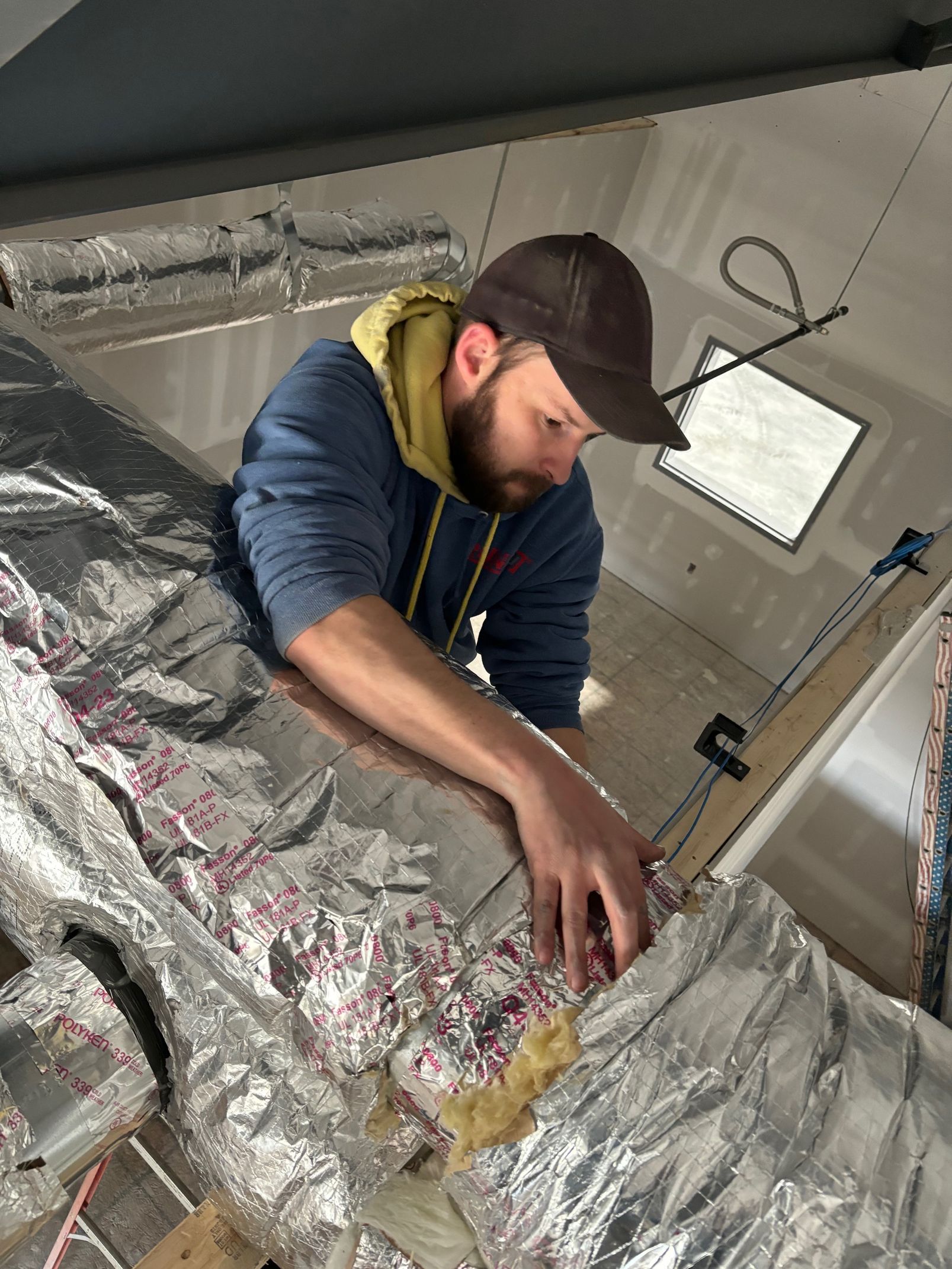A man is working on a piece of aluminum foil.