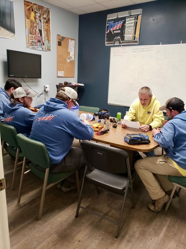 A group of men are sitting around a table in a room.