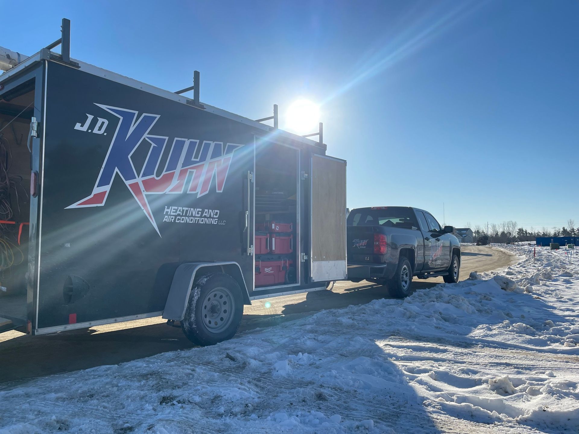 A truck and trailer are parked in the snow.