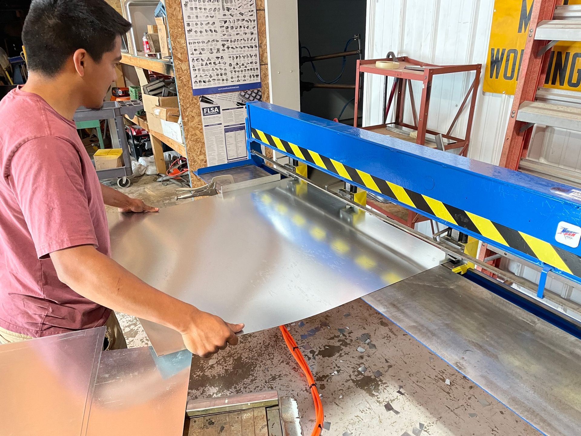 A man is cutting a piece of metal with a machine.