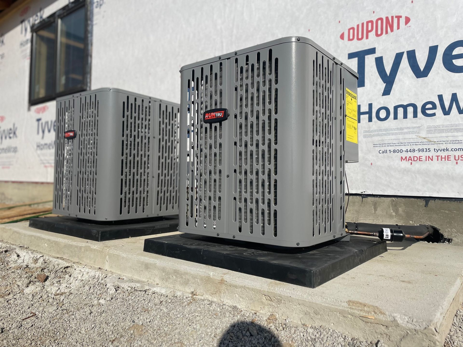Two air conditioners are sitting on top of a concrete platform in front of a building.