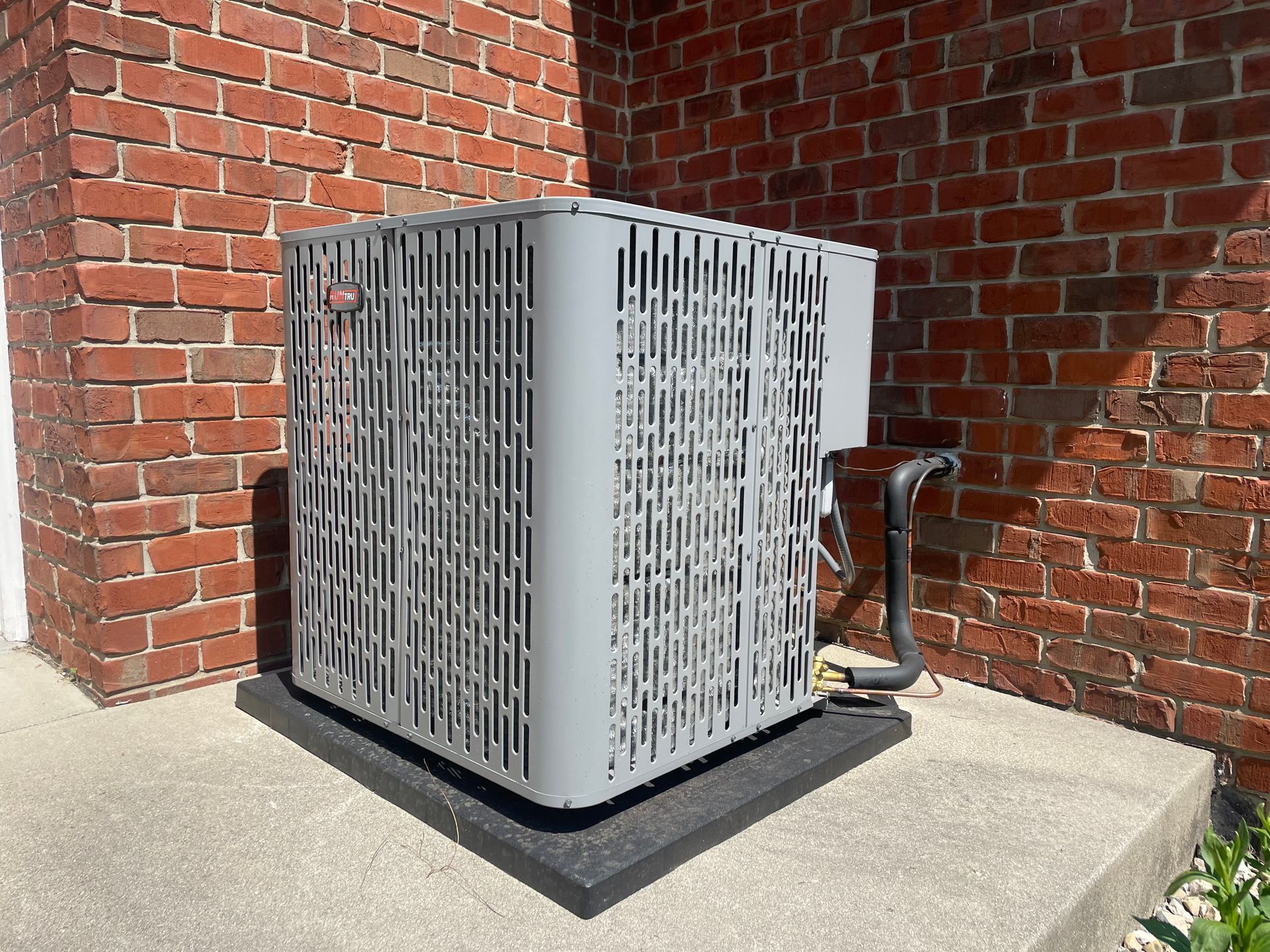 An air conditioner is sitting on the side of a brick building.