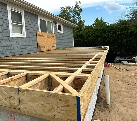 A wooden deck is being built in front of a house.