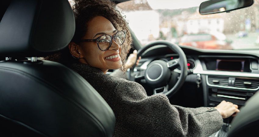 Women driving car wearing glasses smiling back at the passagers