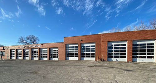 Brick building with several garage doors against a bright blue sky.