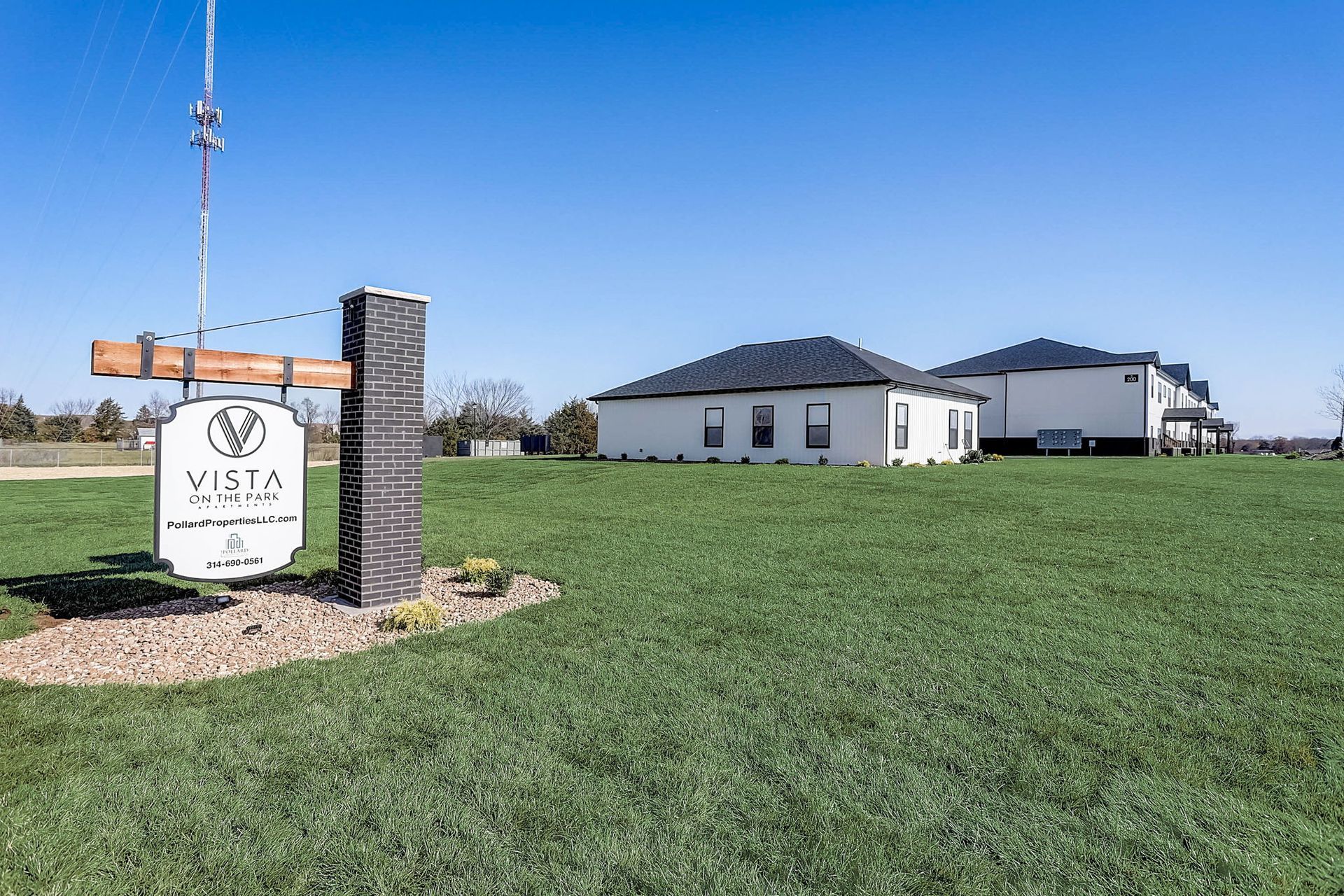 Vista community entrance sign beside a grassy field and white buildings under a clear blue sky