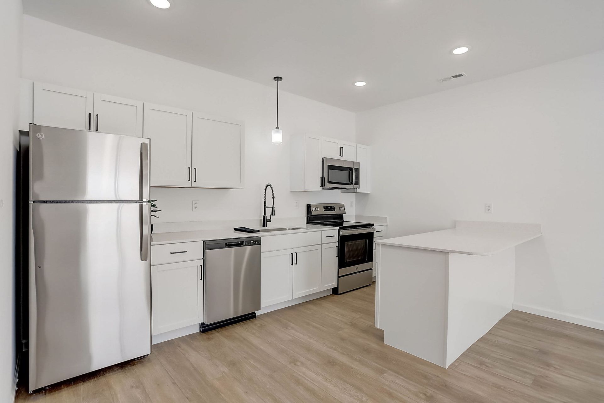 Bright modern white kitchen with stainless steel appliances and a center island, hardwood floors