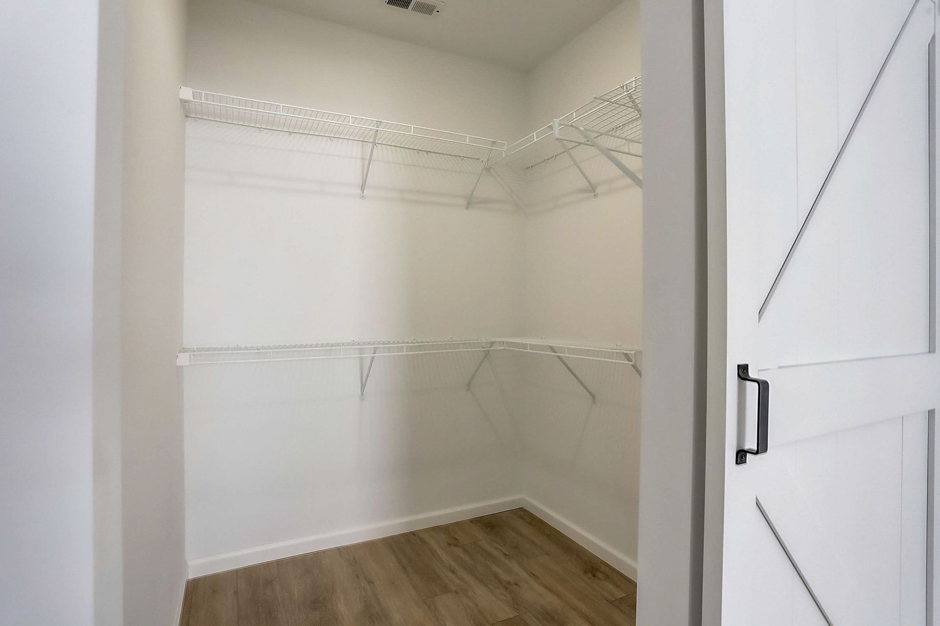 Empty walk-in closet with white wire shelving and wood flooring