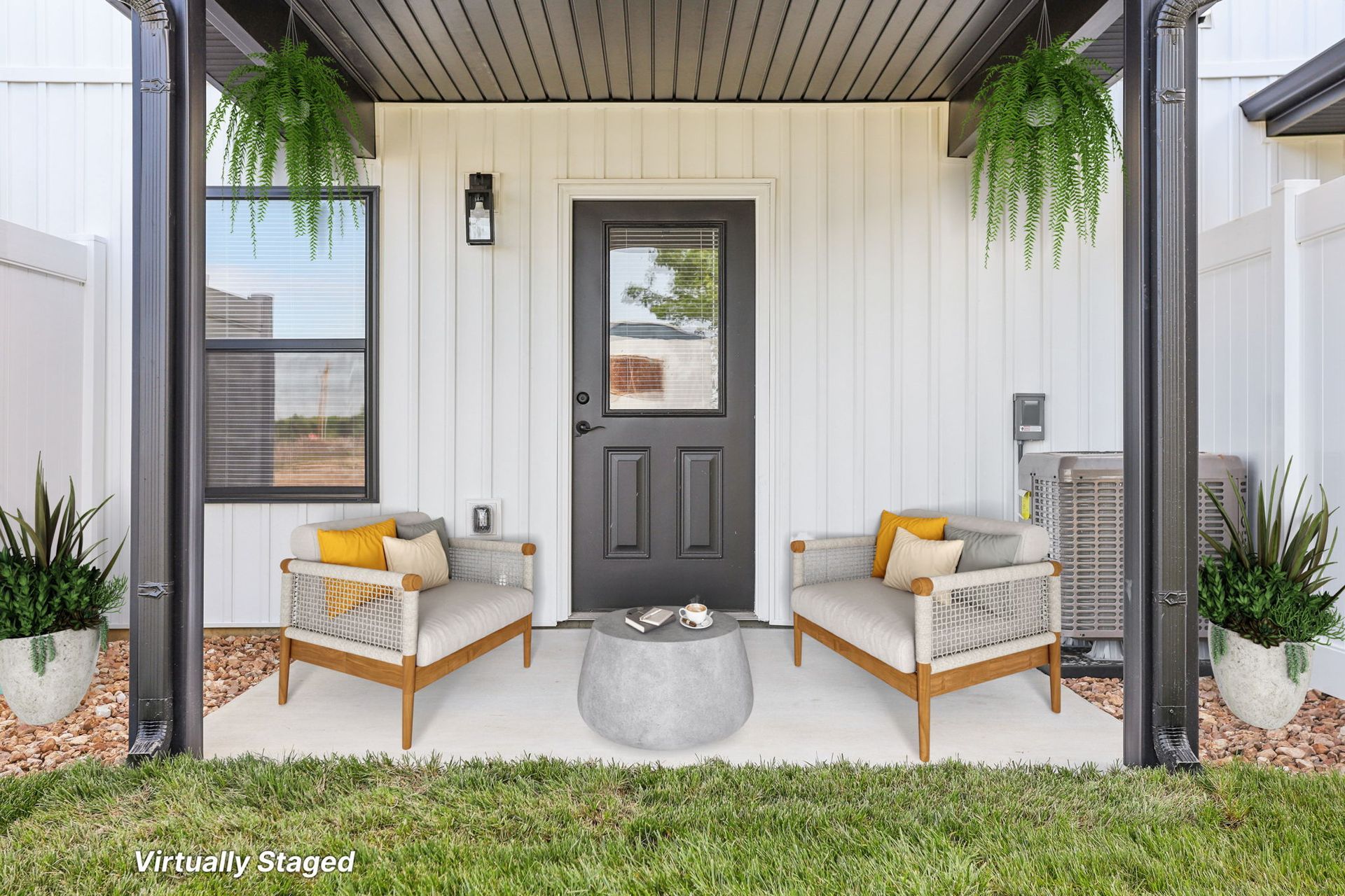 Covered front porch with gray door, wicker chairs, hanging plants, and white siding