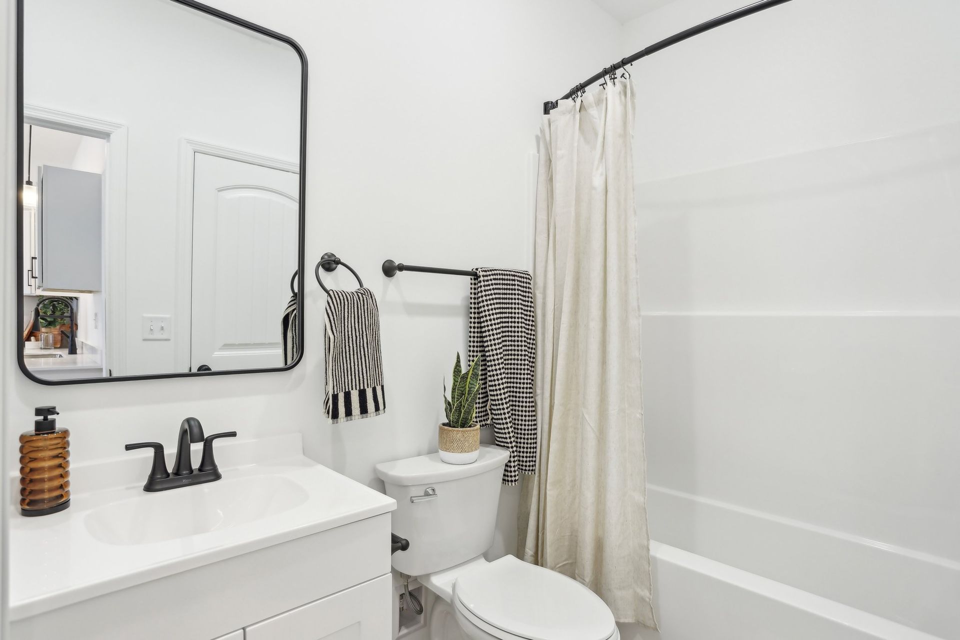 Bright white bathroom with vanity, mirror, toilet, and shower curtain