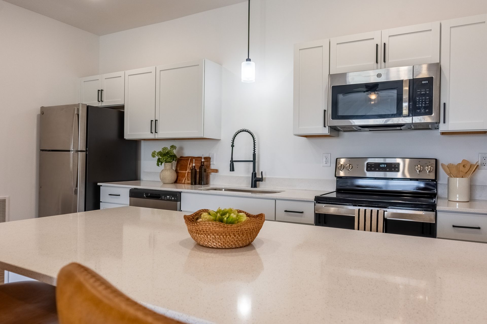 Modern kitchen with white cabinets, stainless steel appliances, island, and bowl of fruit on the counter