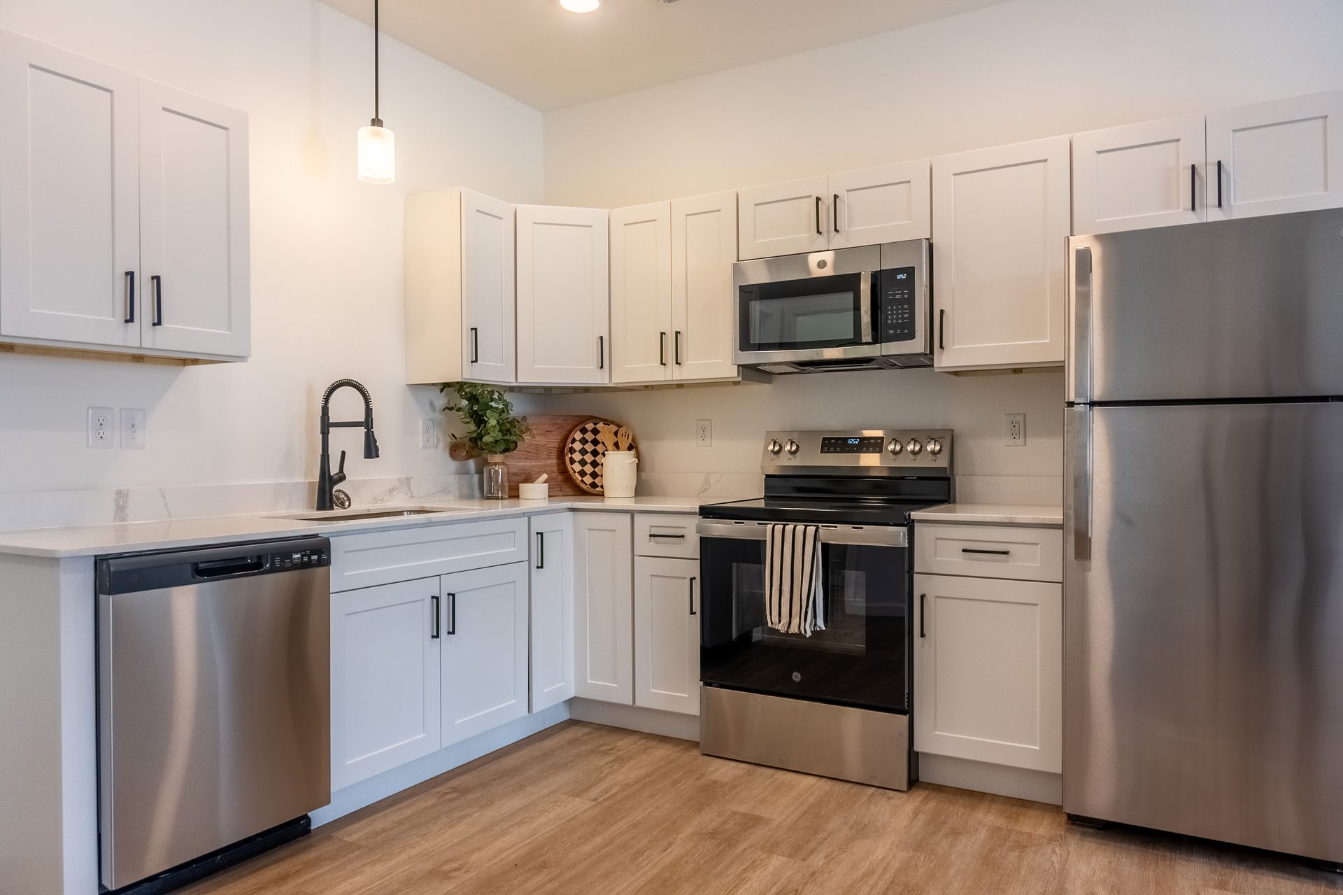 Bright modern kitchen with white cabinets, stainless steel appliances, and wood flooring.