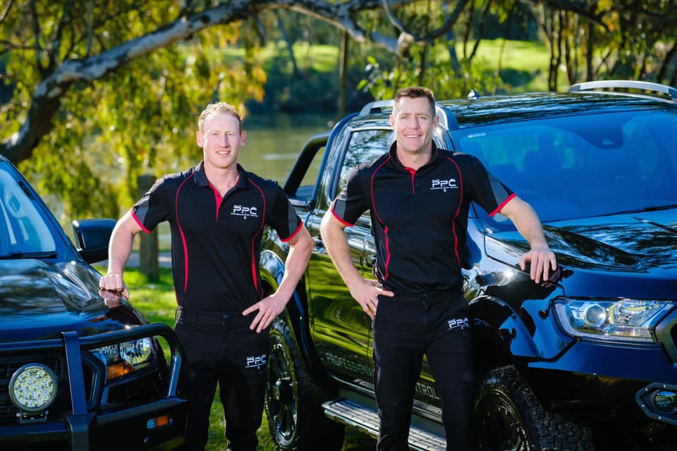 Two Men Standing infront of a car