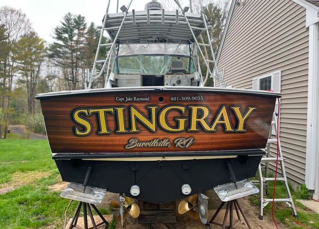 A boat with the name stingray painted on the back is parked in front of a house.