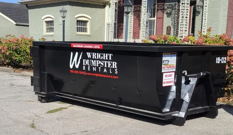 A dumpster for wright dumpster rentals is parked in front of a house