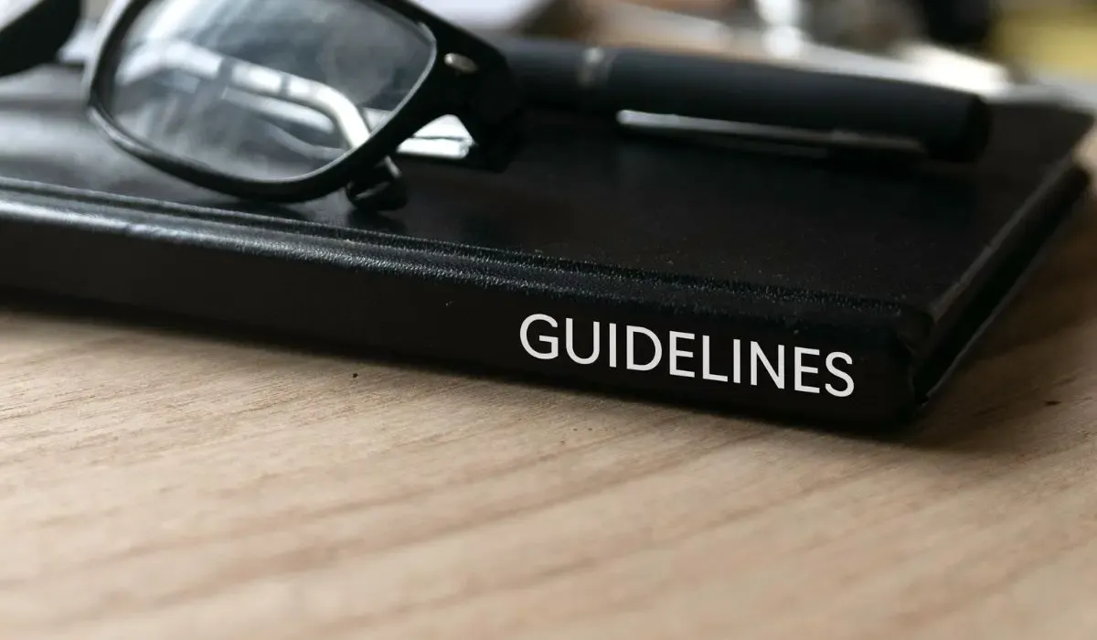 A pair of glasses and a pen are sitting on top of a book called guidelines.