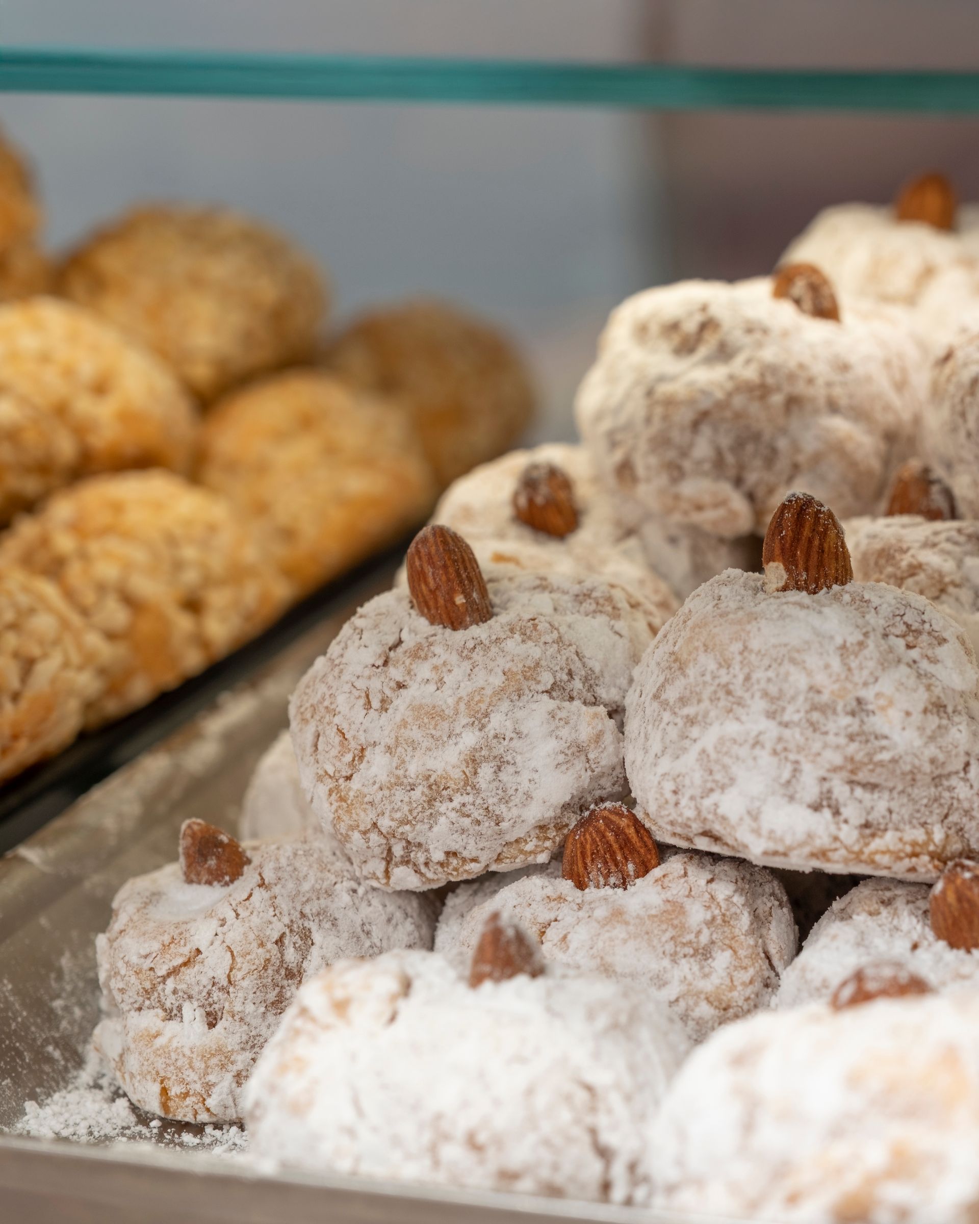 Biscotti spolverati con zucchero a velo e guarniti con mandorle.