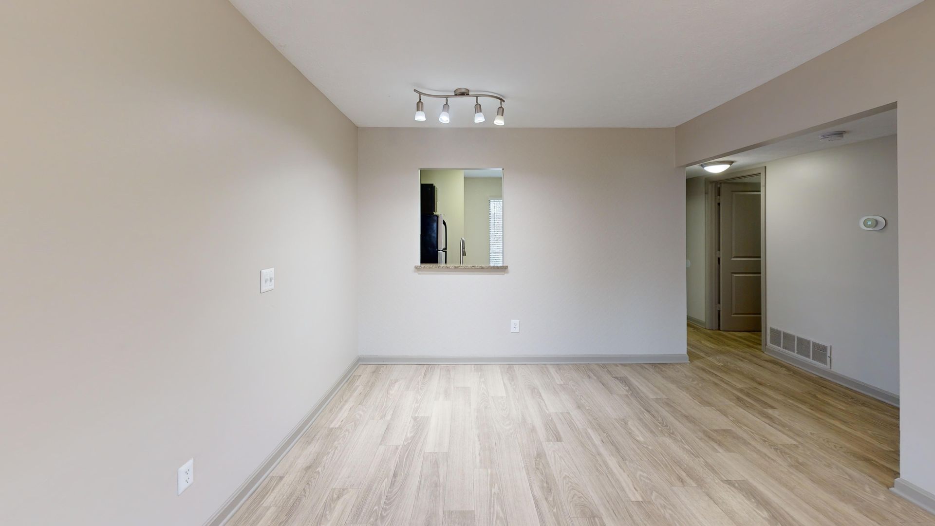 Large living room with plank flooring and a window to the kitchen