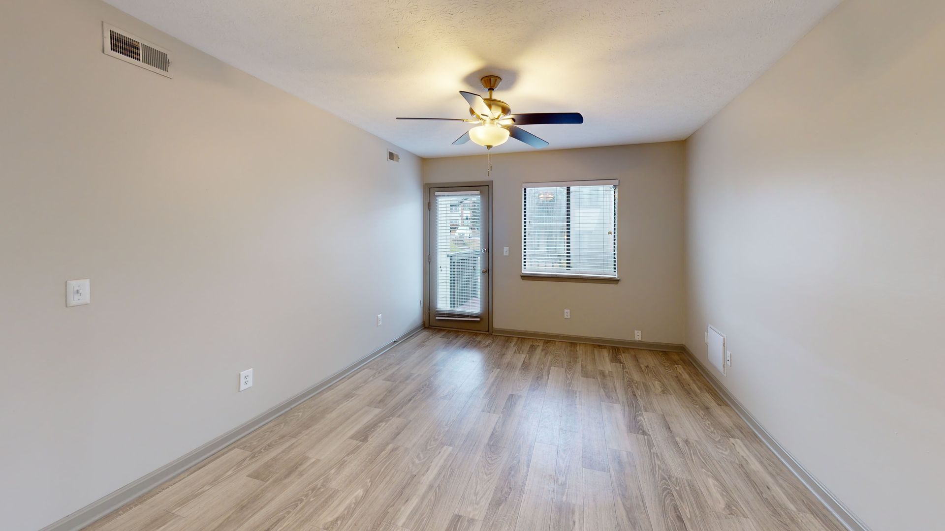 Large living room with plank flooring, a fan, and large windows