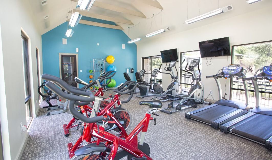 A gym filled with lots of exercise equipment , including treadmills and bikes.