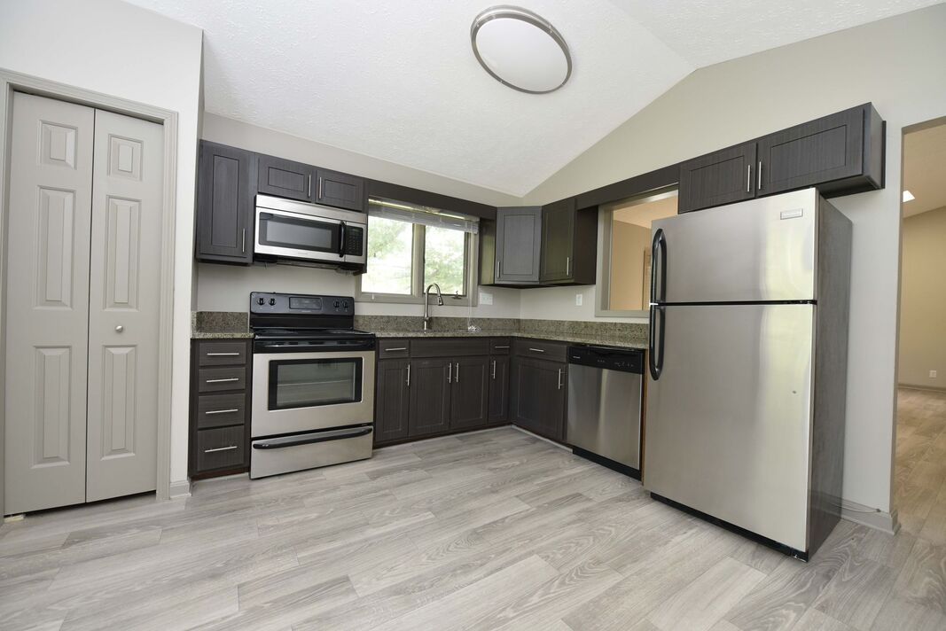 A kitchen with stainless steel appliances and wooden floors.