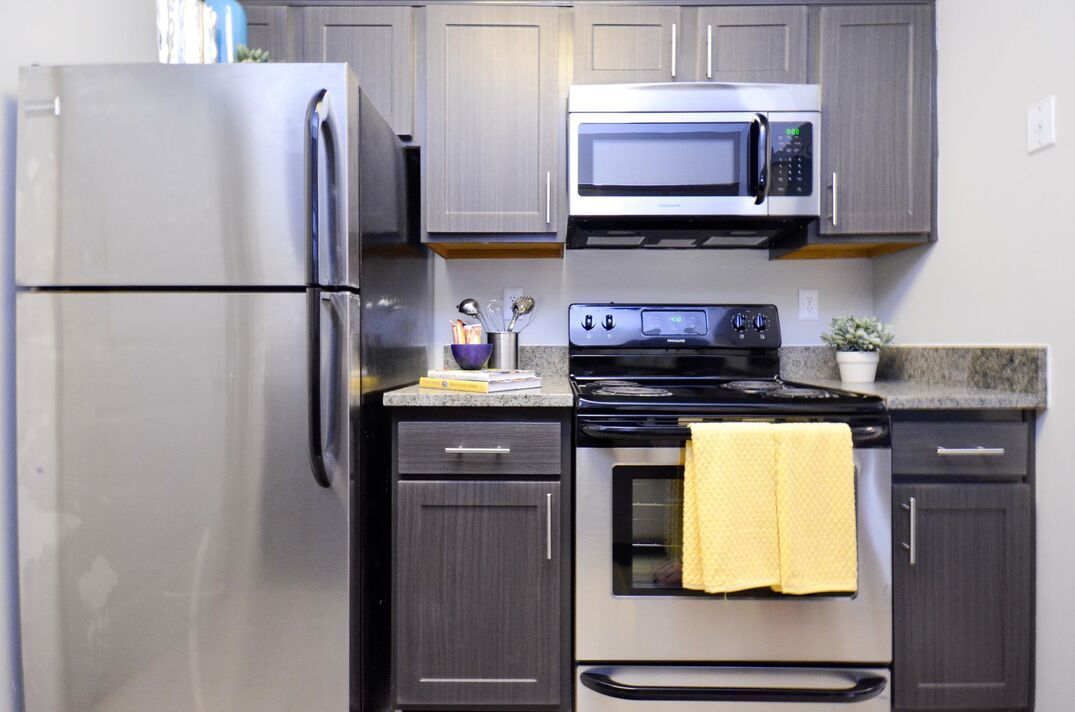 A kitchen with stainless steel appliances and gray cabinets