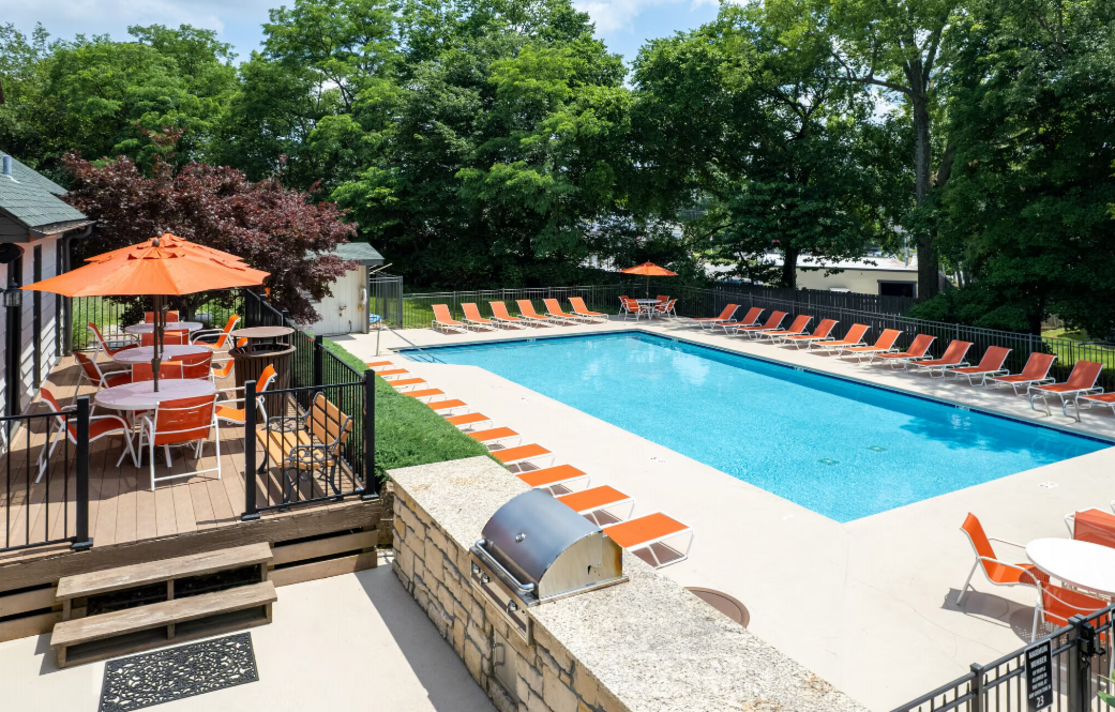 A large swimming pool surrounded by chairs and tables with umbrellas.