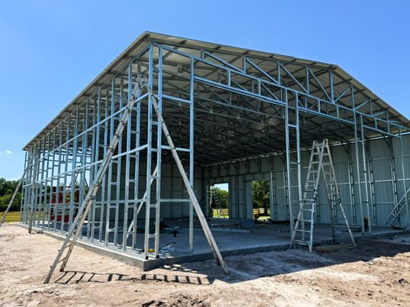 Metal building installation crew assembling steel framing on a Florida property