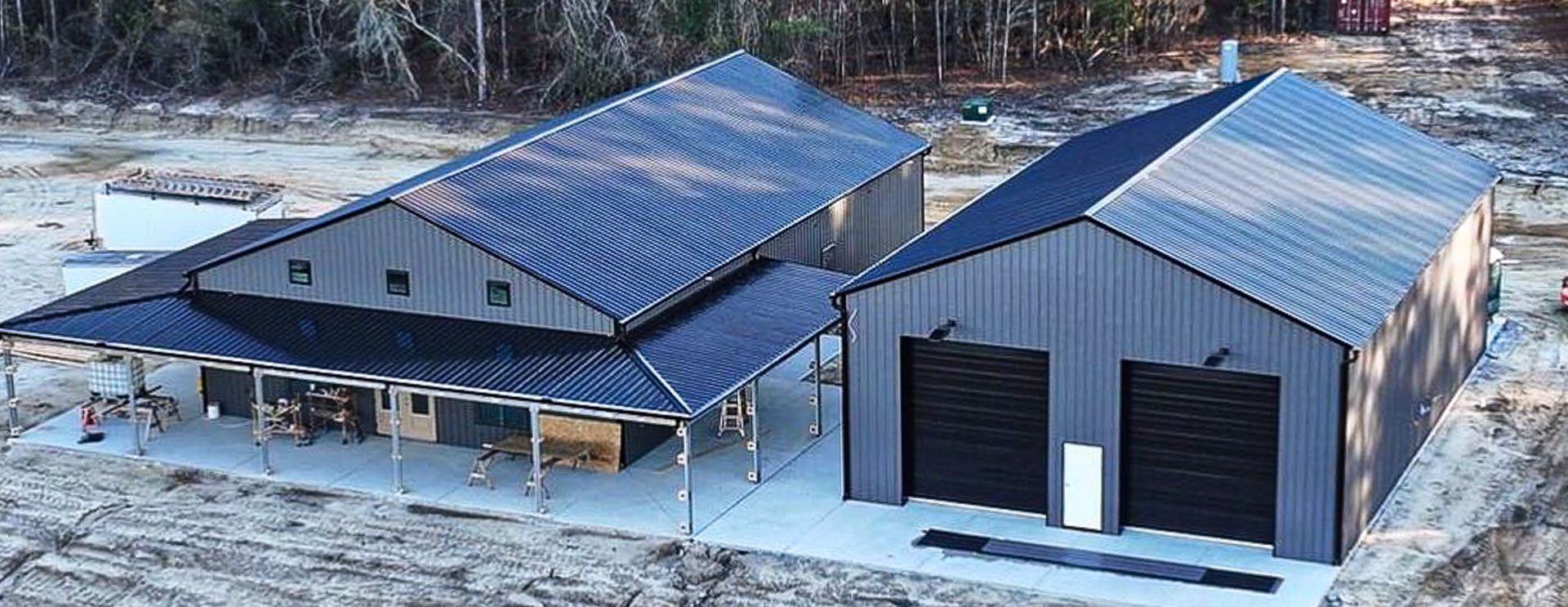 Large metal barn with roll-up doors open and tractor inside