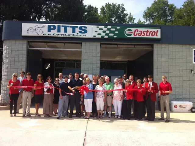 Group of people cutting a red ribbon outside a Pitts/Castrol auto shop | Pitts Automotive