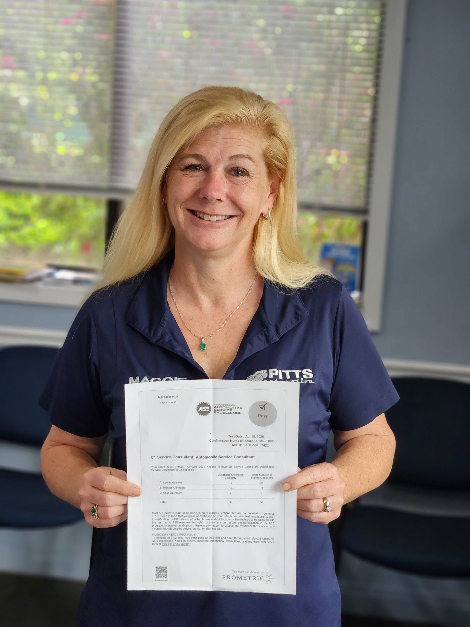 Woman in navy shirt holding a document and smiling indoors by a window. | Pitts Automotive