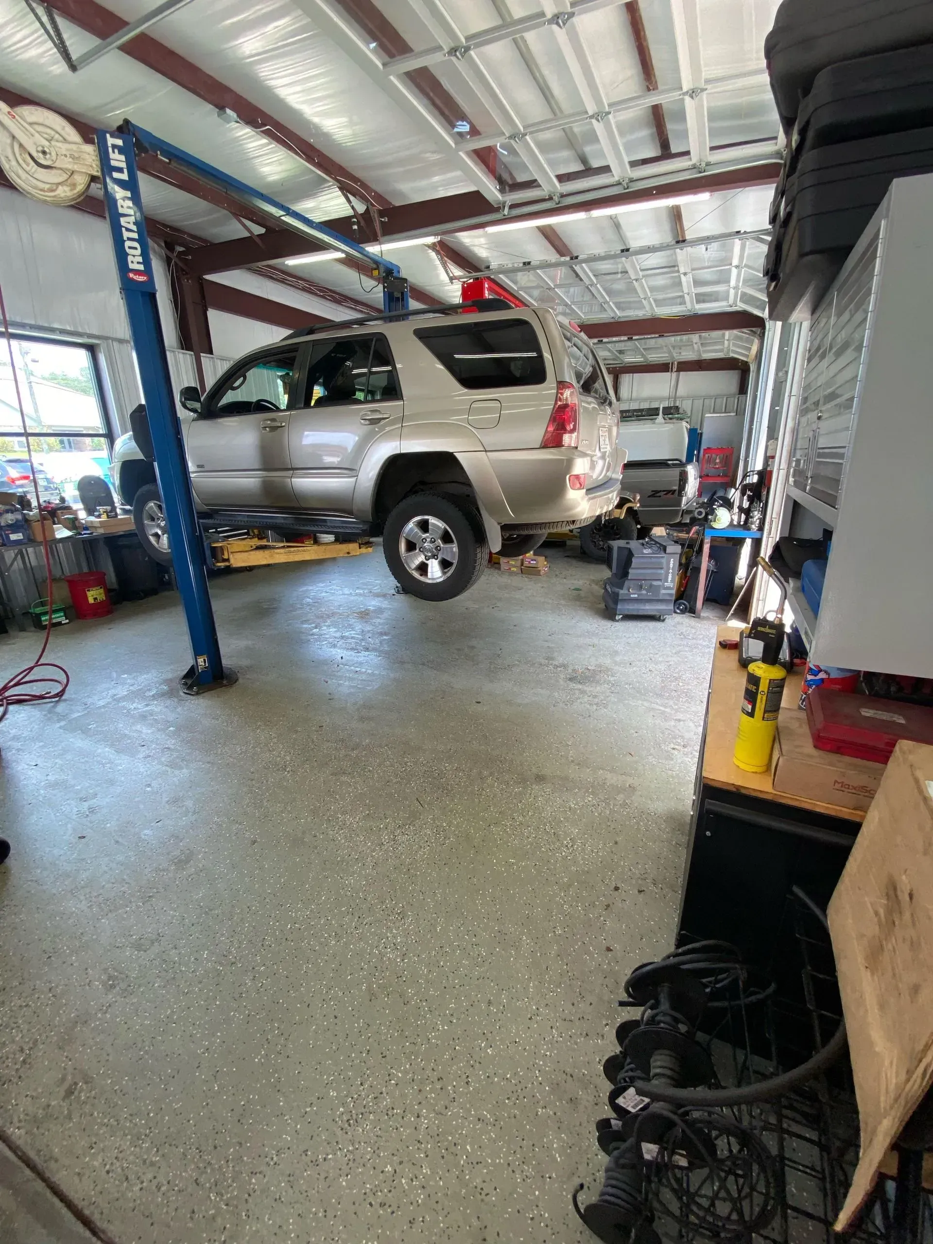 Silver SUV lifted on a blue hoist in an auto repair garage | Pitts Automotive