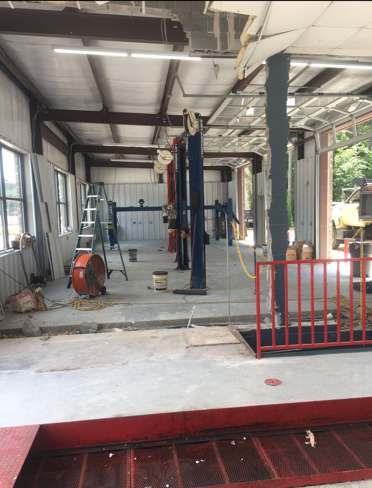 Industrial workshop with exposed ceiling beams, equipment, and a red safety barrier near the entrance | Pitts Automotive