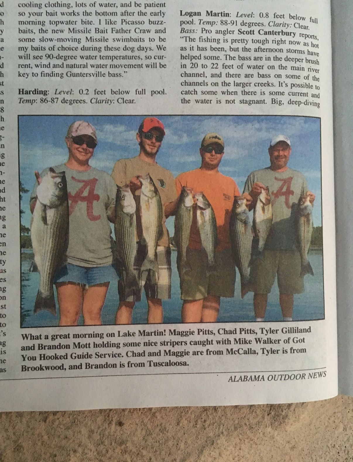 Four men in red caps and gray/orange shirts hold large fish, standing outdoors by the water. | Pitts Automotive