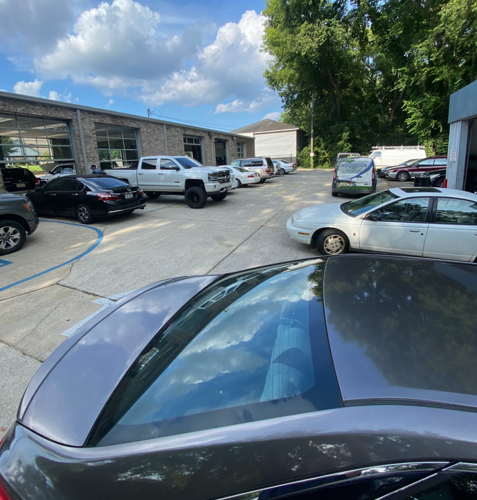 Parking lot with cars beside low apartment buildings under a partly cloudy sky | Pitts Automotive
