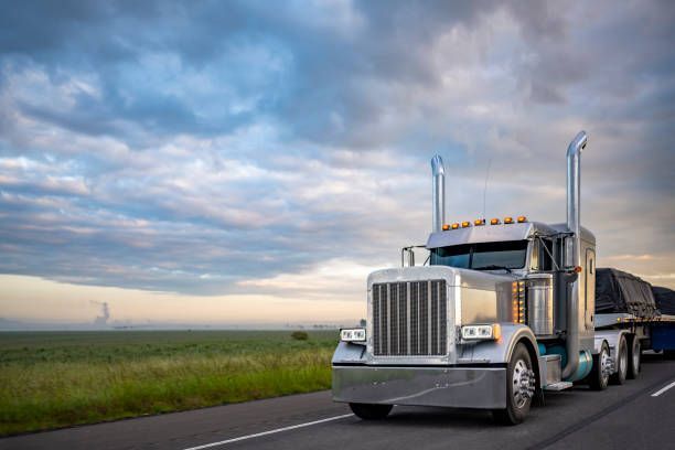 Chrome semi truck pulling a trailer down an open highway under a cloudy sky