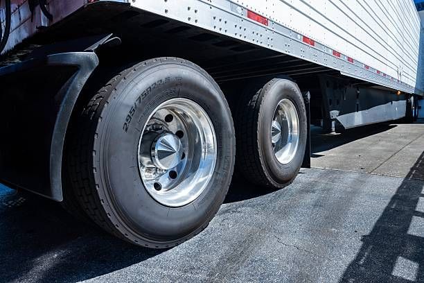 Trailer tires with polished wheels under a white semi trailer
