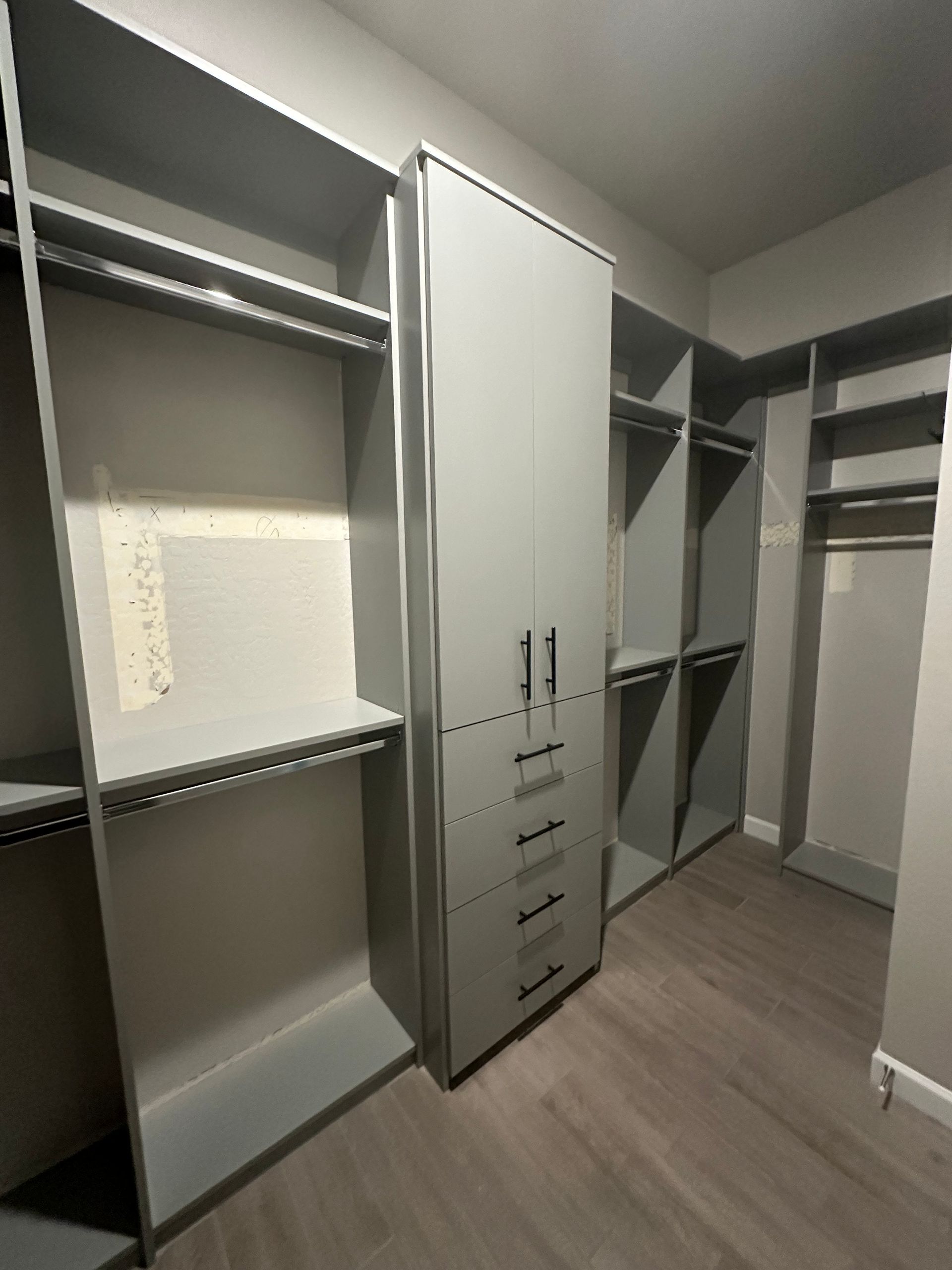A walk in closet with lots of shelves and drawers