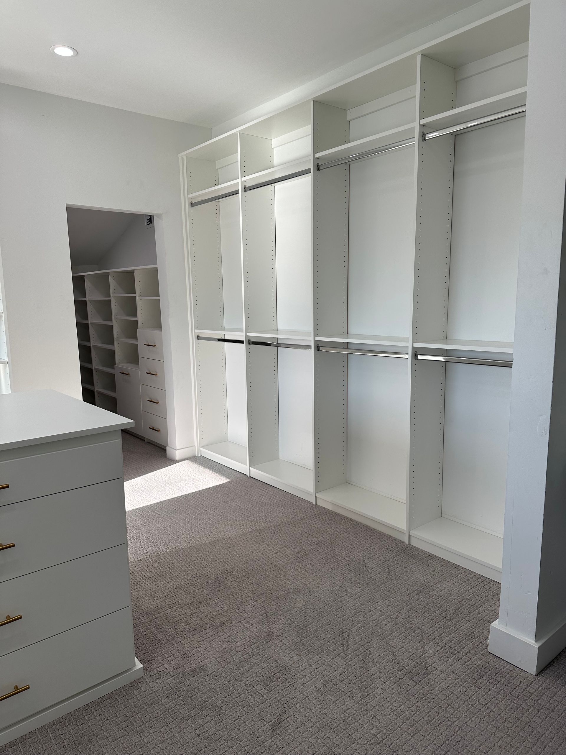 A walk in closet with lots of shelves and clothes racks.