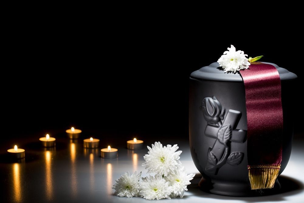A Black Urn With Flowers and Candles on a Table — Becker Family Funerals In Port Macquarie, NSW