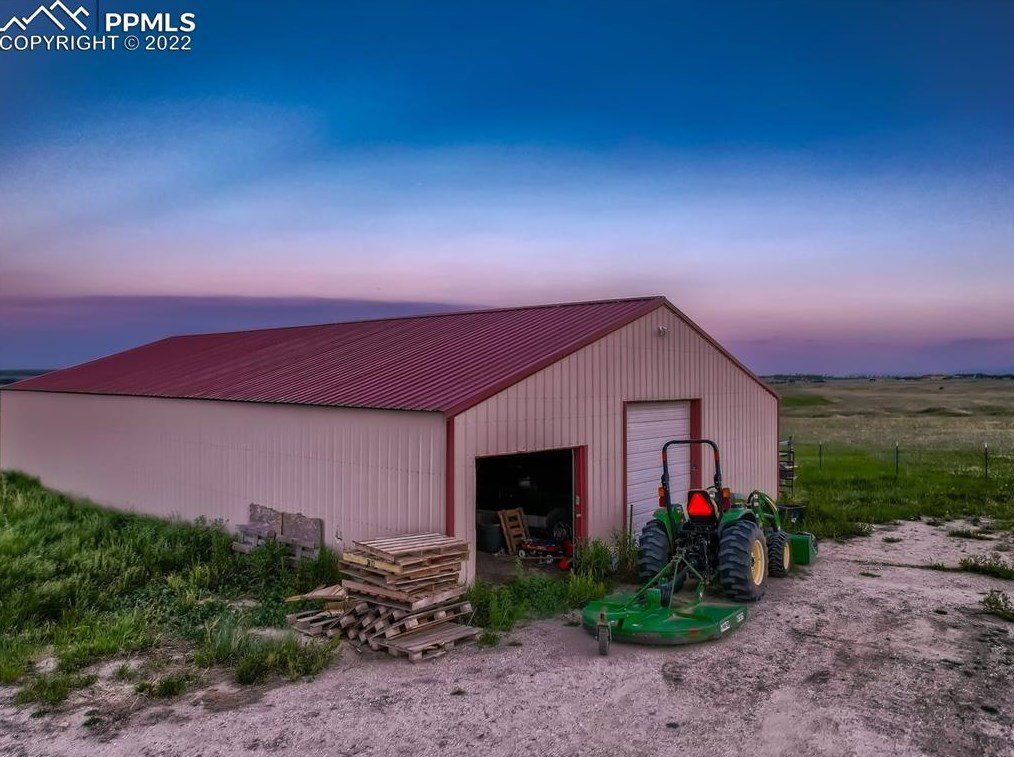An aerial view of a barn with a tractor parked in front of it.