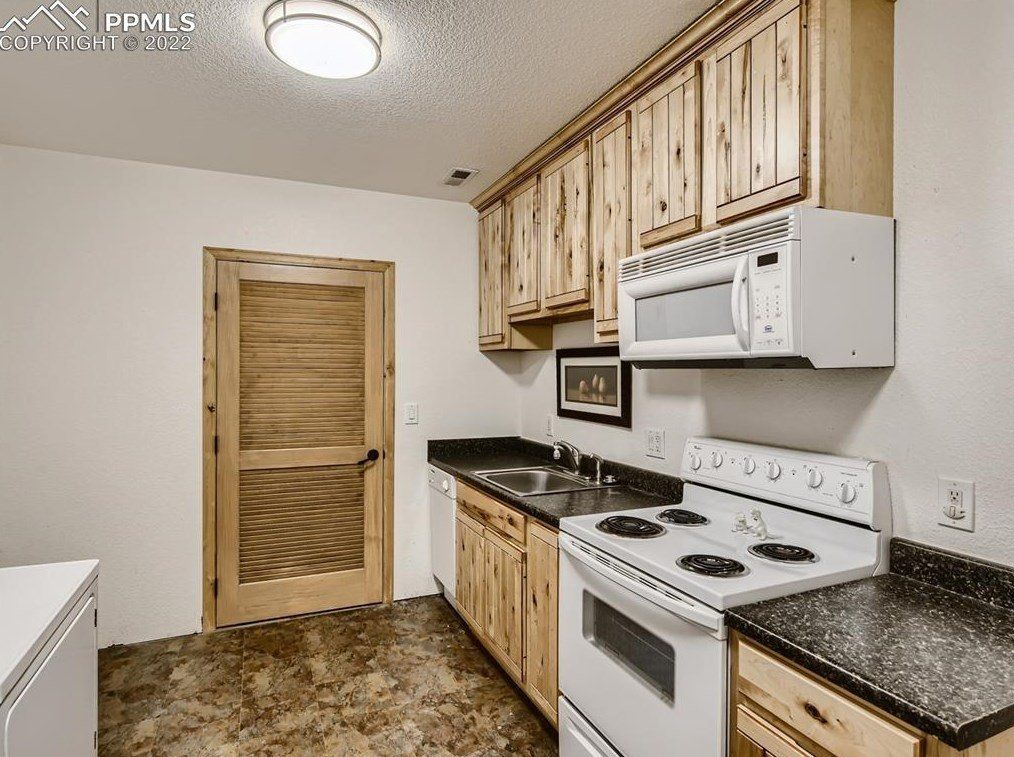 A kitchen with a stove , microwave , sink and cabinets.