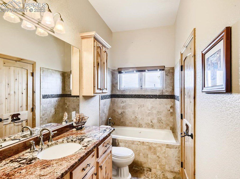 A bathroom with a sink , toilet , tub and mirror.