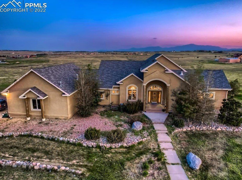 An aerial view of a large house in the middle of a field.