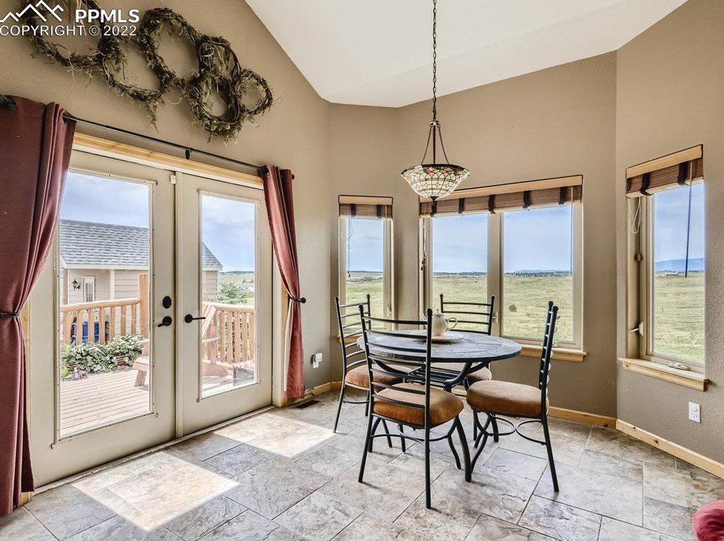 A dining room with a table and chairs and lots of windows