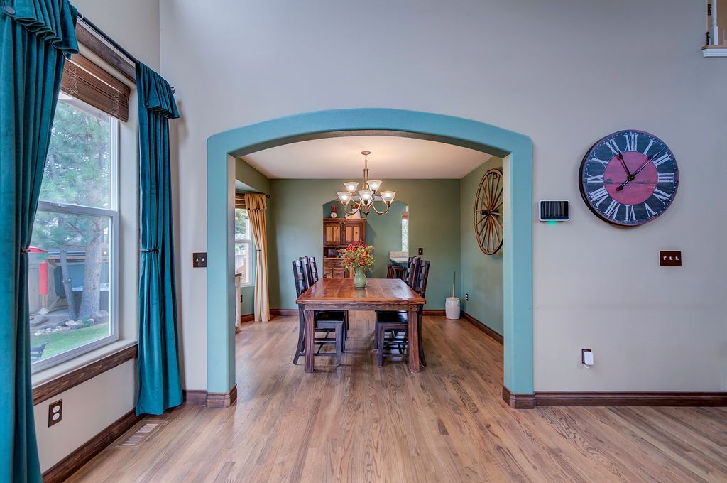 A dining room with a table and chairs and a clock on the wall.