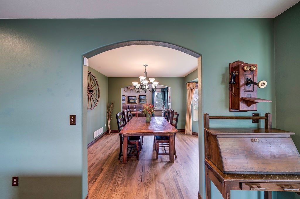A dining room with a wooden table and chairs and green walls.