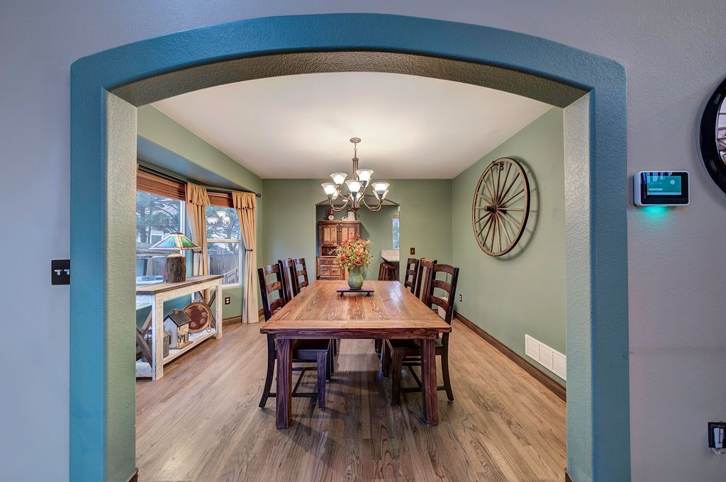 A dining room with a wooden table and chairs and a clock on the wall.