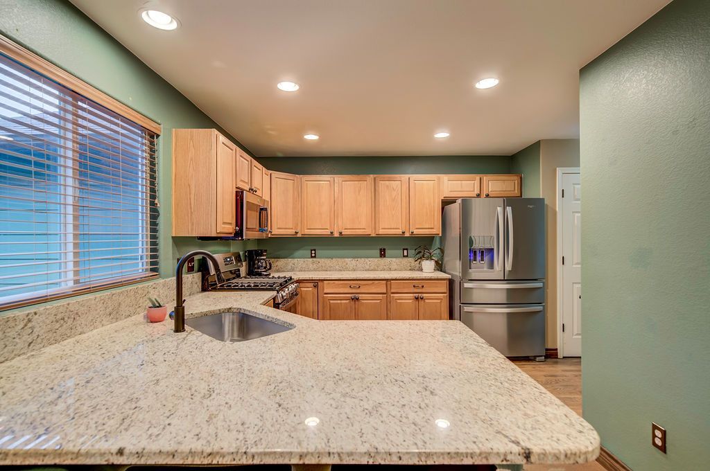 A kitchen with granite counter tops , stainless steel appliances , and wooden cabinets.