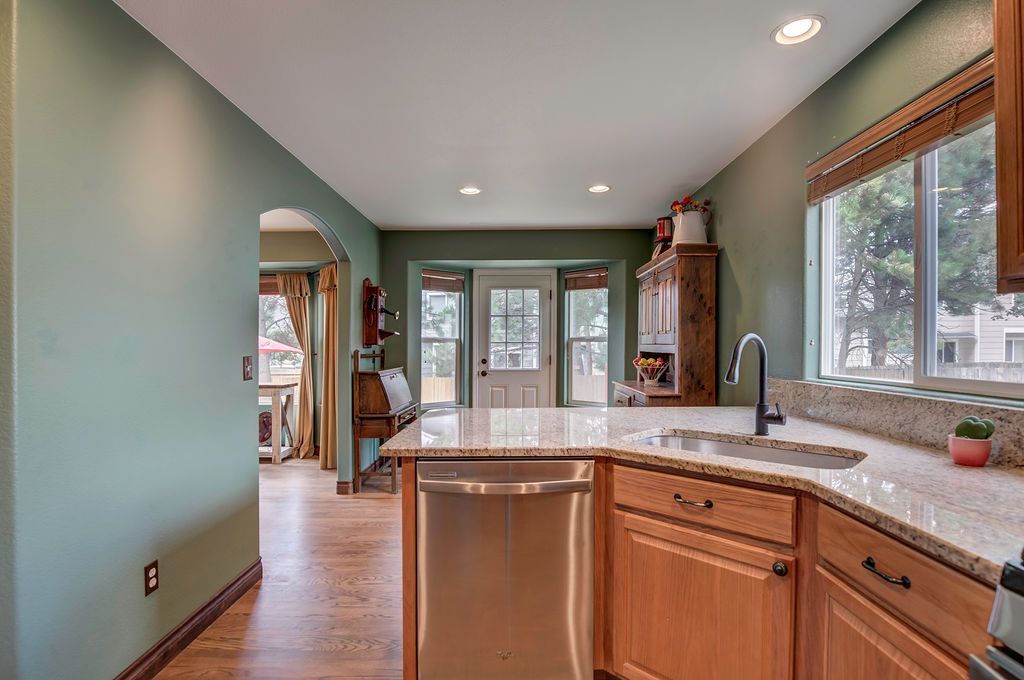 A kitchen with stainless steel appliances , wooden cabinets , granite counter tops and a large island.